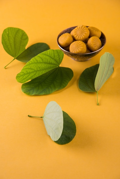 Festival indio dussehra, mostrando hoja de oro con dulces tradicionales indios pedha en tazón de plata sobre fondo amarillo, tarjeta de felicitación