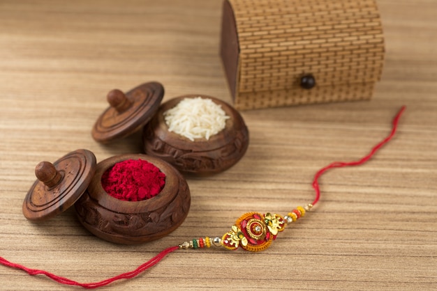 Foto festival indio: fondo de raksha bandhan con un elegante rakhi, granos de arroz y kumkum