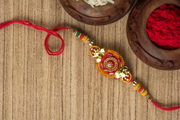 Festival indio: fondo de Raksha Bandhan con un elegante Rakhi, granos de arroz y Kumkum