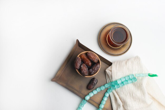 Festival Ramadan Kareem, fechas en un tazón de madera con una taza de té negro y rosario