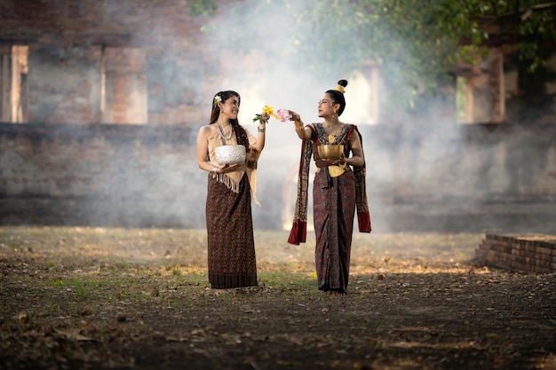 Festival songkran. a garota em traje nacional tailandês está espirrando água no dia de songkran.