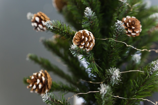 Festive uma árvore de Natal artificial com cones e sem enfeites.