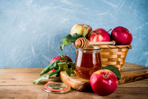 Festividad judía Rosh Hashaná o concepto de fiesta de manzana, con manzanas rojas, hojas de manzana y miel en frasco