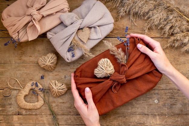 Foto festivo llanamente de regalos embalados en estilo furoshiki sobre fondo de madera