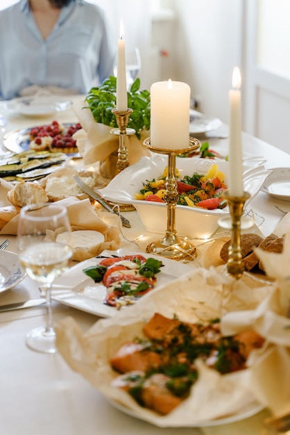 Festlich gedeckter Tisch zum Abendessen mit frischen Speisen und Weißwein, geschmückt mit Kerzen