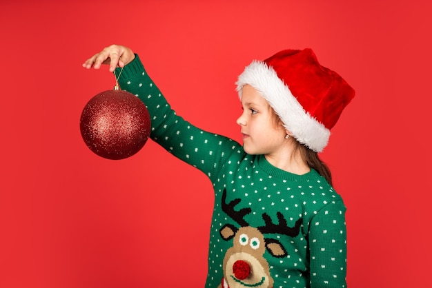 Festliche Dekoration. bereit für Weihnachtsfeier. schöne Winterferien. Gruß und Glückwünsche. kleiner Weihnachtsmann-Helfer. Fröhliches Kind hält Neujahrsgeschenk. Geschenkdekoration und Paketversand. Frohe Weihnachten.