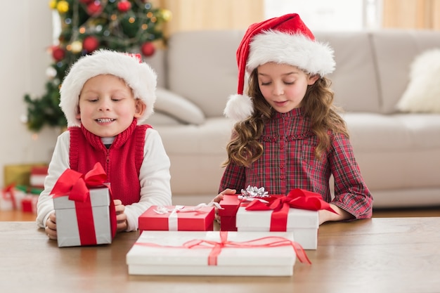 Festliche Geschwister, die an ihren Geschenken lächeln