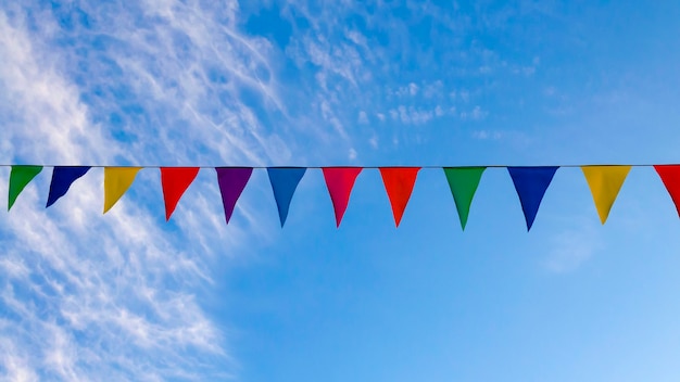 Foto festliche girlanden, flatternde farbige bänder, blauer himmel hintergrund, website-cover über fröhliche stimmung, festival.