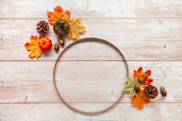 Festliche Herbstdekoration aus Kürbisblättern und Eicheln auf Holzhintergrund