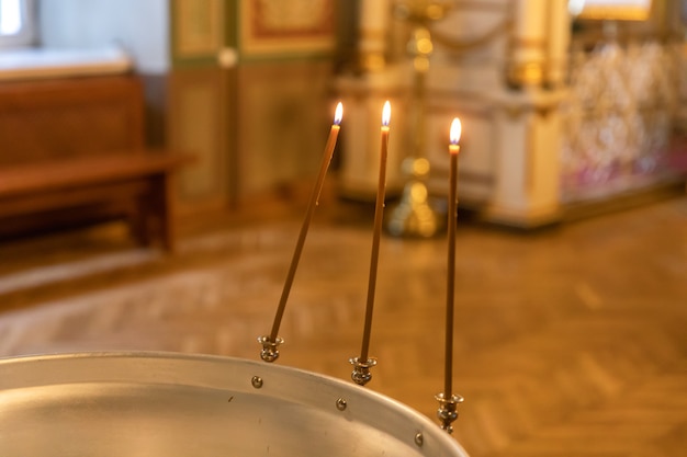 Festliche Innendekoration des orthodoxen Kirchenchristentums mit brennenden Kerzen und Ikone in...
