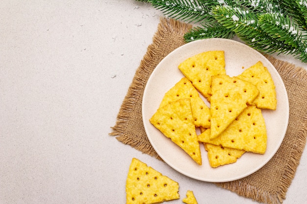 Festliche Käsecracker, Snackkonzept des neuen Jahres. Plätzchen, Tannenbaumast, künstlicher Schnee, Sackleinen-Serviette.