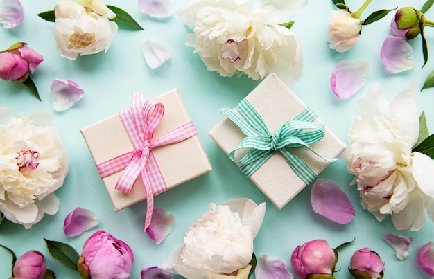 Festliche Komposition auf blauen Pastell Hintergrund Pfingstrosen Blumen Geschenkboxen Draufsicht Kopienraum