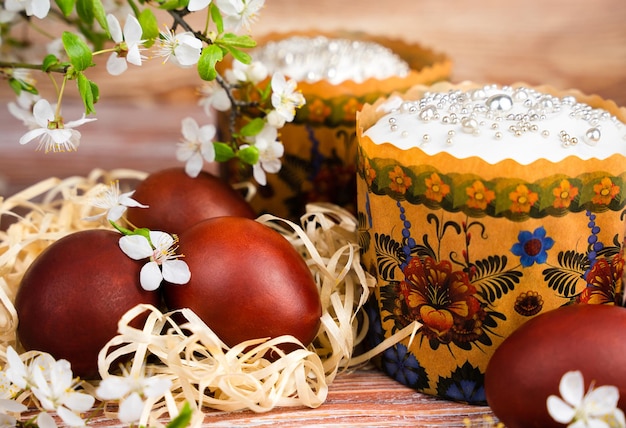 Festliche Komposition mit farbigen Eiern und mit weißem Glasur geschmückten Osterkuchen Nahaufnahme