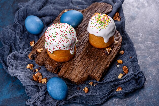 Festliche Kuchen mit weißer Glasur, Nüssen und Rosinen mit Ostereiern auf dem festlichen Tisch