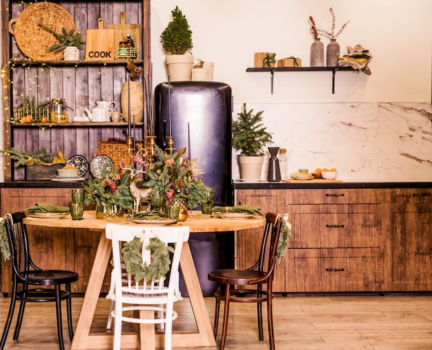 Festliche Küche in Weihnachtsdekorationen. Kerzen, Fichtenzweige, Holzständer, Tischdecken. Foto