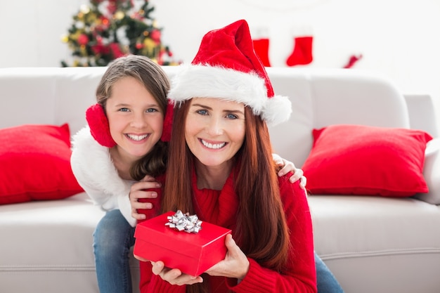 Festliche Mutter und Tochter mit einem Weihnachtsgeschenk