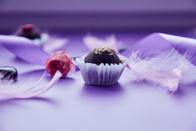 Festliche Schokoladenbonbons mit Nüssen und rosa Rose Trendige rosa Federn und lila Band Sehr peri pantone Farbmuster