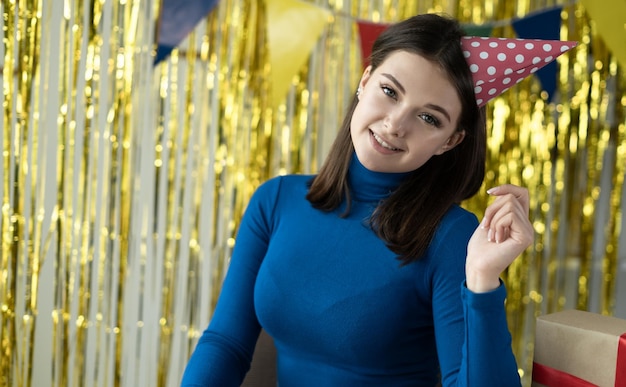 Festliche Stimmung genießen Sie die Party Geburtstagsmädchen junge lächelnde Dame in einer festlichen Mütze schaut auf die Kamera und lächelt