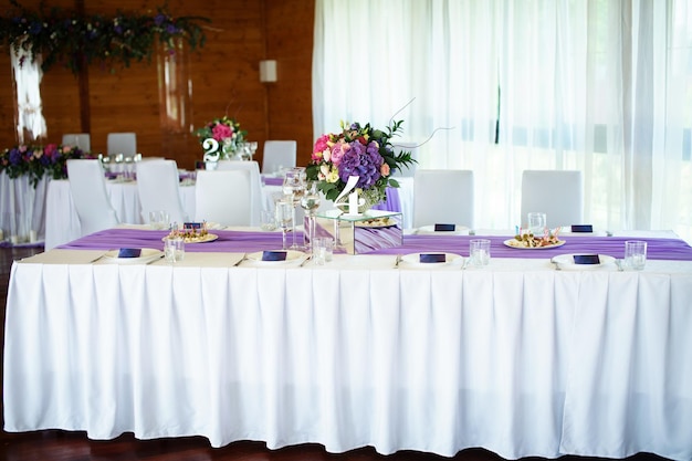 Festliche Textildekoration im Restaurant mit Blumenarrangements auf dem Tisch neben den Tellern