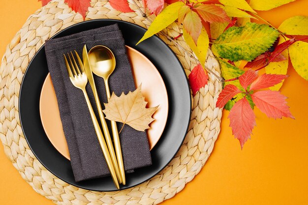 Festliche Tischdekoration mit hellem Herbstlaub auf pastellfarbenem Hintergrund.