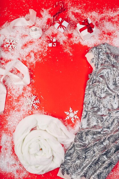 Foto festliche weihnachtsattribute und dekorationen auf einem roten hintergrund geschenkkisten und paillettenkleid auf der