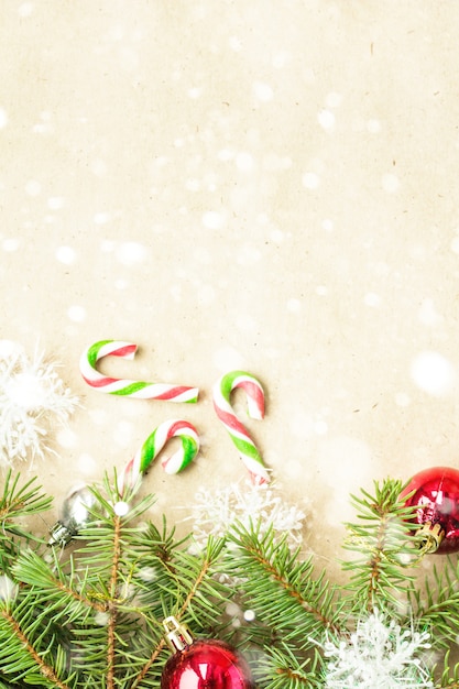 Festliche Weihnachtsgrenze mit den roten und silbernen Bällen auf Tannenzweigen und Schneeflocken auf rustikalem beige Hintergrund des Schnees
