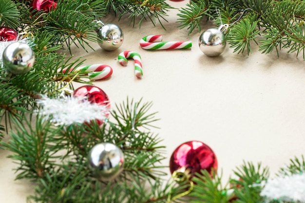 Festliche Weihnachtsgrenze mit den roten und silbernen Bällen auf Tannenzweigen und Schneeflocken auf rustikalem beige Hintergrund