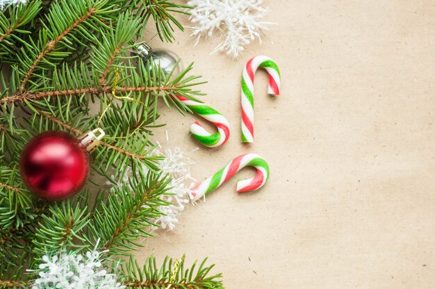 Festliche Weihnachtsgrenze mit den roten und silbernen Bällen auf Tannenzweigen und Schneeflocken auf rustikalem beige Hintergrund