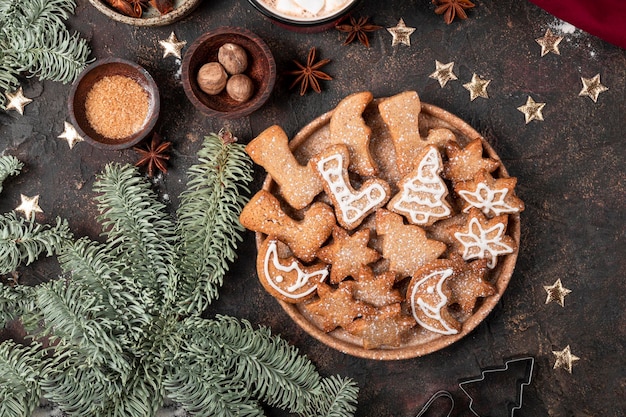 festliche Weihnachtsplätzchen dekoriert mit Puderzucker und Puderzucker auf einem Teller mit dunklem Hintergrund oben