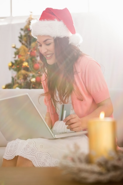 Festlicher Brunette, der online mit Laptop am Weihnachten kauft