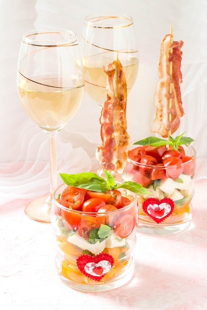 Festlicher Caprese-Salat mit gebratenem Speck am Spieß in Gläsern
