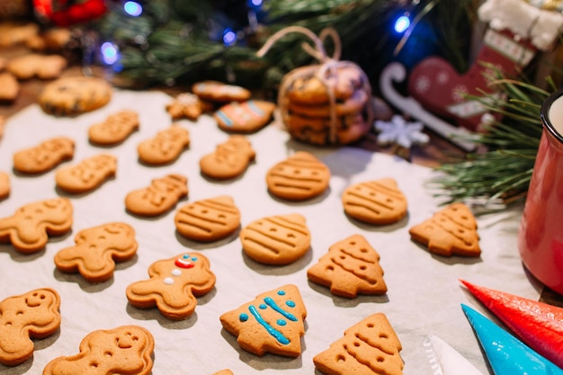 Festlicher Hintergrund der Weihnachtsbäckerei aus nächster Nähe Icing hausgemachte Lebkuchenplätzchen auf dem Kochblatt Familienfeier Feiertagsdekoration und Neujahrstraditionen Konzept