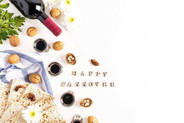 Festlicher Hintergrund des jüdischen Pessachfestes mit koscherem Matzah-Rotwein und silbernen Glasnüssen auf weißem Hintergrund mit dem Text Happy Pessach