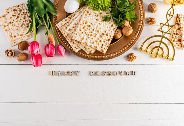 Festlicher Hintergrund für den Frühlingsfeiertag des jüdischen Passahs Traditionelle Speisen Blumen kleiner Kerzenstock Text des glücklichen Passahs