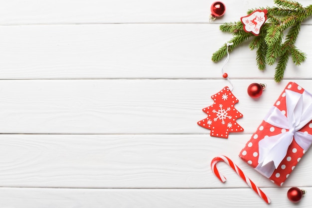 Festlicher Hintergrund mit einem Weihnachtsbaumgeschenk und einer Zuckerstange auf einem weißen Holztisch. Platz kopieren. Flache Lage, Ansicht von oben.