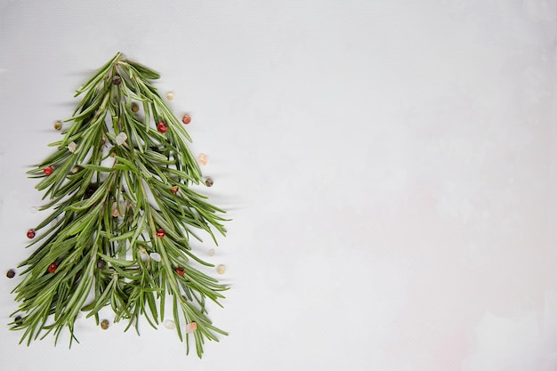 Festlicher kreativer Weihnachtsbaum aus Rosmarin und dekoriert mit Pfefferkörnern und Meersalz Saisonales Styling Grüner HintergrundKopienplatz