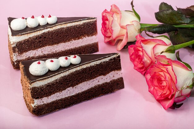 Festlicher Kuchen mit Schokoladen- und Quarkschicht. Zwei Portionen. Auf einem rosa Hintergrund. Geburtstag, Feiertage, Süßigkeiten. Speicherplatz kopieren.