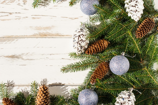 Festlicher Neujahrshintergrund mit Platz für Ihren Text. Fichtenzweige, Wald- und Silberkegel, blau funkelnde Kugeln. weißer hölzerner Hintergrund.