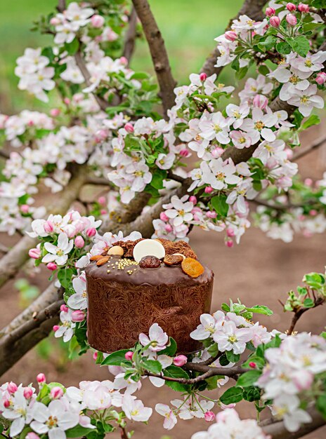 Festlicher Osterkuchen auf dem Hintergrund eines blühenden Apfelbaums im Garten. Apfelbaum blüht an einem klaren sonnigen Tag.