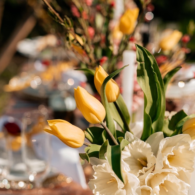 Festlicher Rahmen mit schönen Tulpen auf dem Esstisch, der für die Osterfeier serviert wird