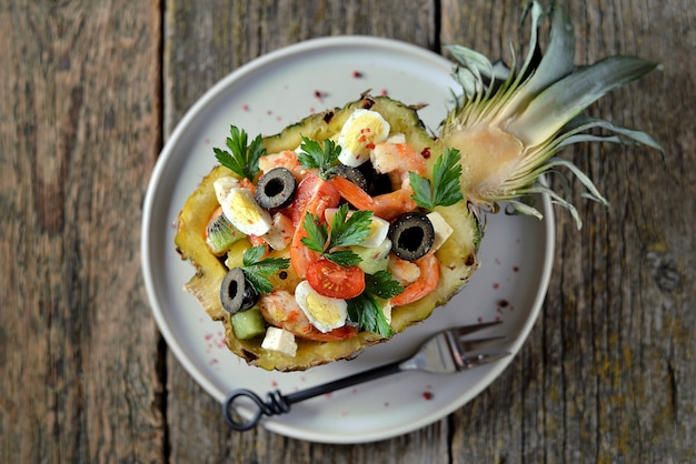 Festlicher Salat aus Garnelen, Kiwi, Oliven, Weichkäse, Wachteleiern, Kirschtomaten in Ananastellern.