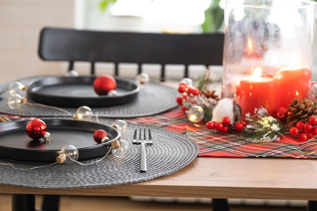 Festlicher Tisch im Wohnzimmer für Weihnachten und Neujahr im Loft-Stil Weihnachtsbaum schwarze Teller und Gabeln gewebte Servietten trendiges Geschirr gemütliches Interieur des Hauses