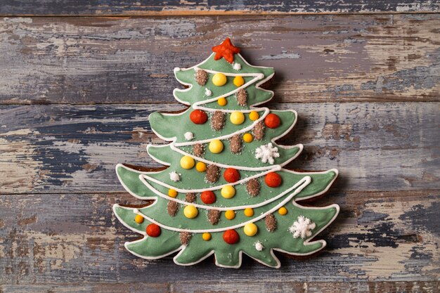 Festlicher Weihnachts- und Neujahrslebkuchen in der Form des Tannenbaums auf blauem hölzernem Hintergrund, flache Lage.