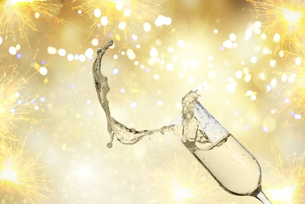 Festliches Champagnerglas mit Spritzer auf goldenem Bokeh-Hintergrund mit Lichtern