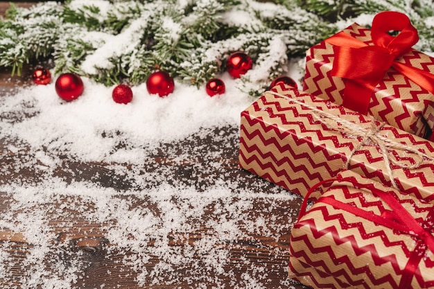 Festliches Geschenk mit Bogen nah oben auf hölzernem Hintergrund mit Schnee