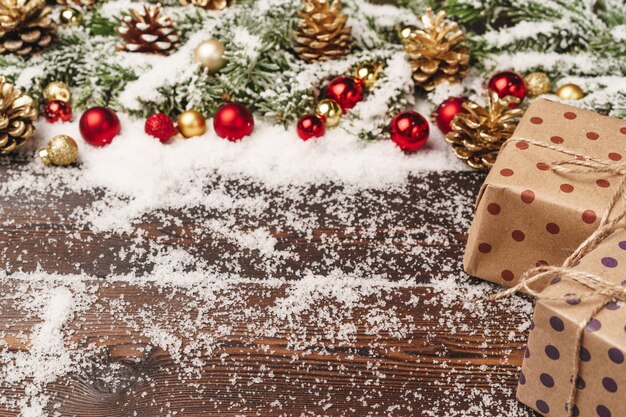 Festliches Geschenk mit Bogenabschluß oben auf hölzernem Hintergrund mit Schnee