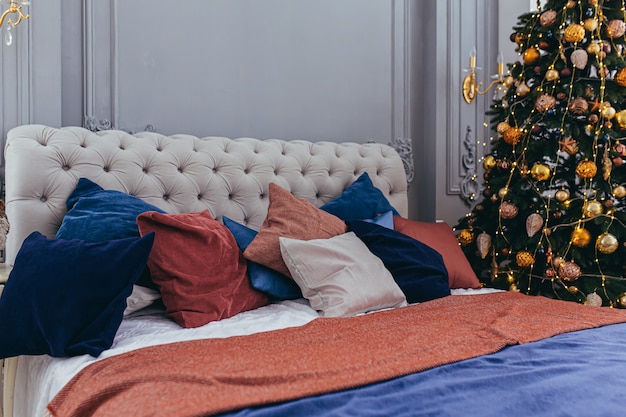 Festliches großes Bett im Hotelzimmer mit geschmücktem Weihnachtsbaum