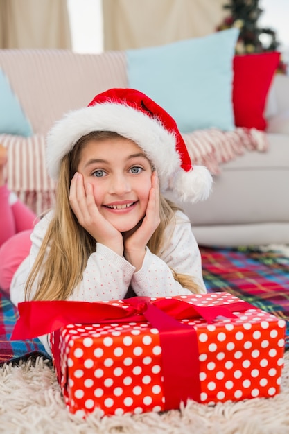 Festliches kleines Mädchen, das an der Kamera mit Geschenk lächelt