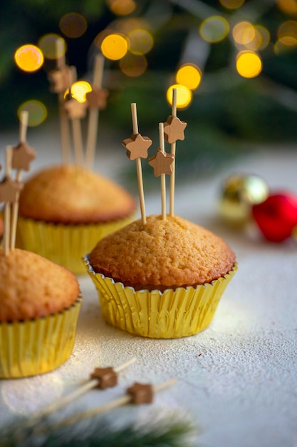 Festliches Neujahrsdessert. Cupcakes, dekoriert mit Holzsternen am Spieß auf einem weißen Tisch.