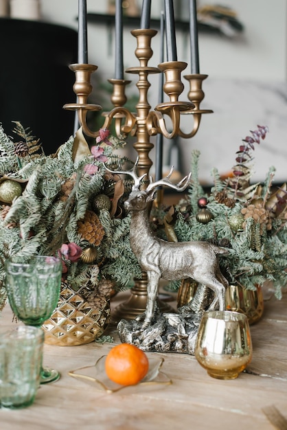 Festliches Weihnachtsessen Einstellung Hirsch-Souvenir-Kerzen in einer Kerzenständer-Gläser-Mandarine und Tannen- oder Fichtenzweigen in einer Vase